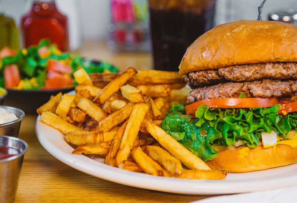 A hamburger and french fries on a white plate on a table.