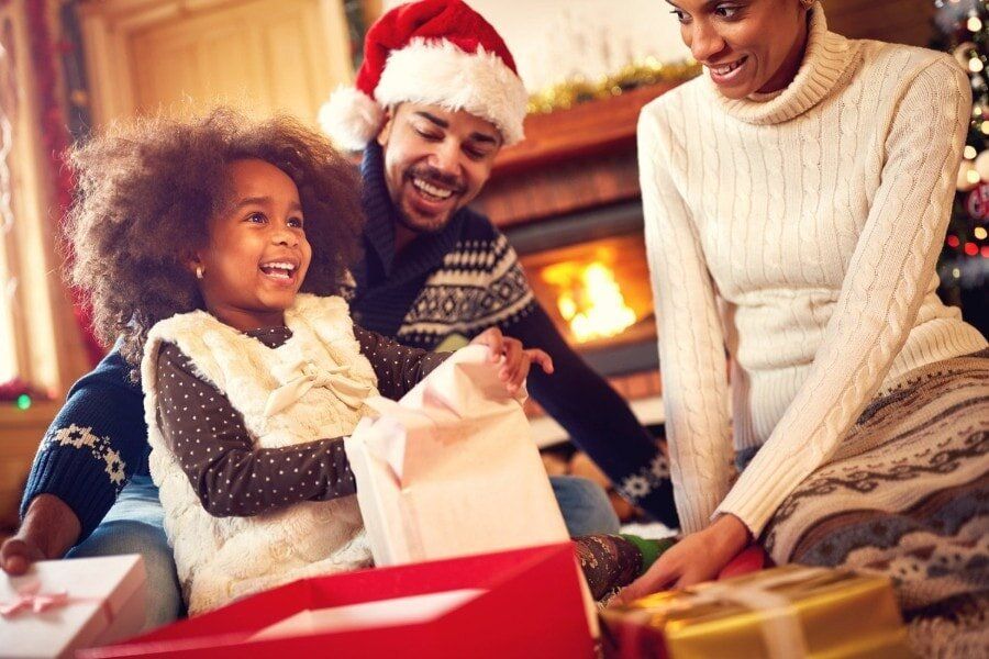 A family is opening christmas presents in front of a fireplace.