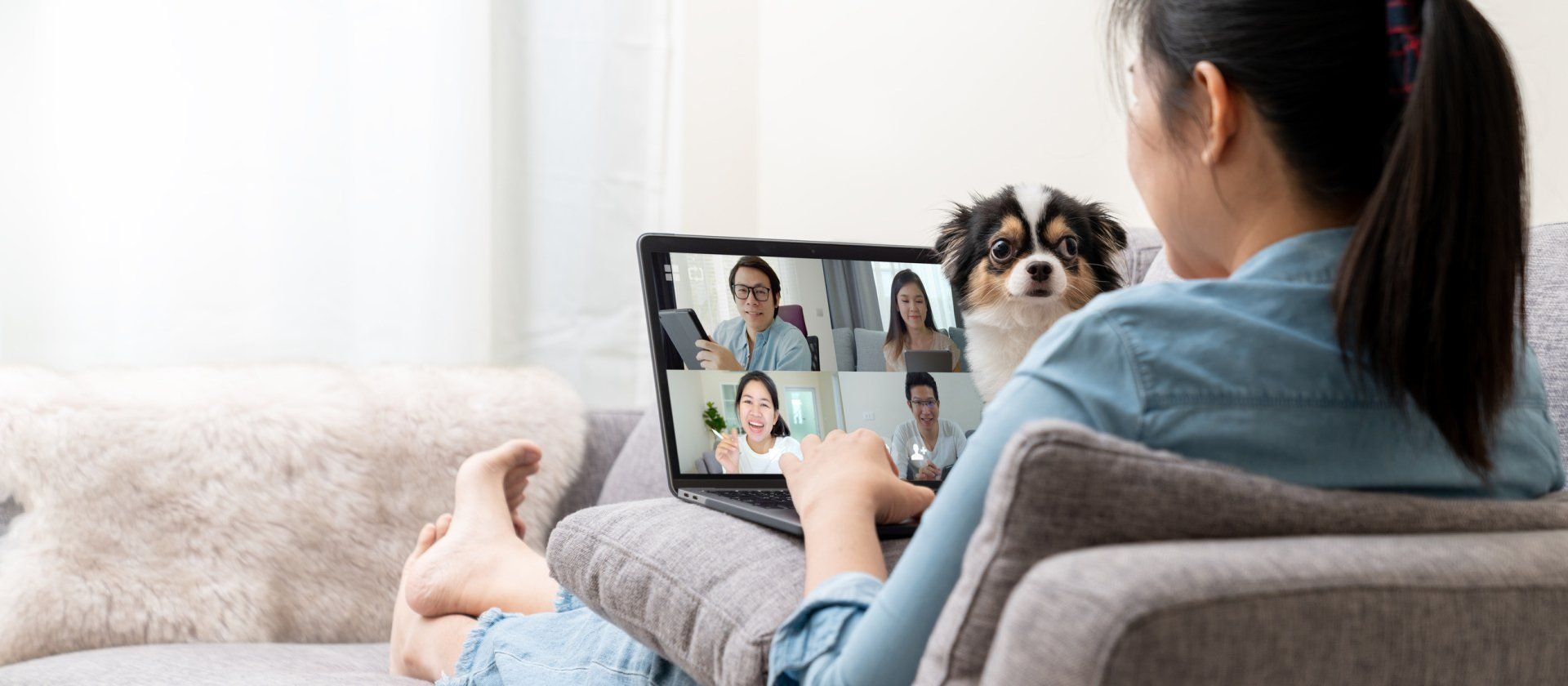 Woman on video call with dog on couch.