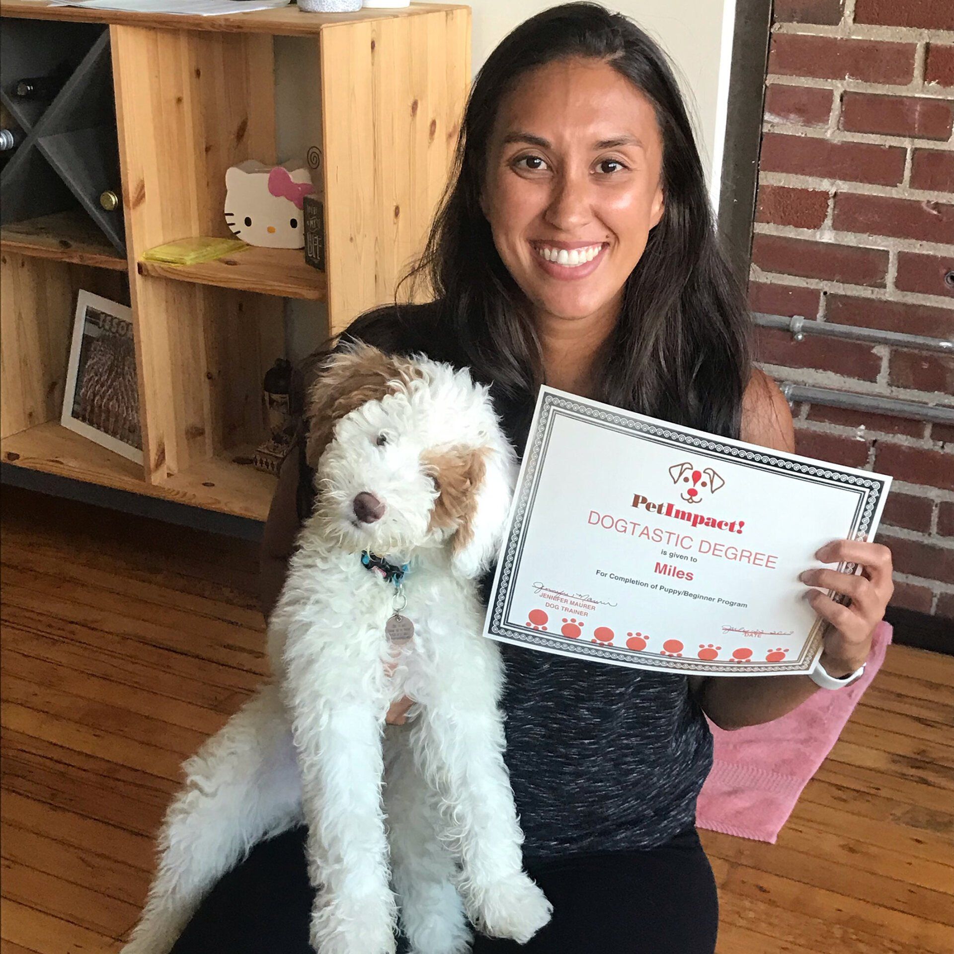 Woman smiles, holding a fluffy white and brown dog and a 
