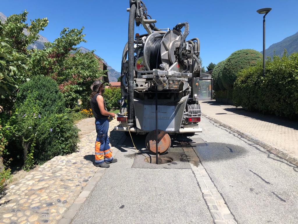 Une femme se tient à côté d'une grosse machine sur le bord de la route.