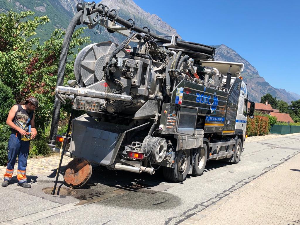 Un homme se tient à côté d'un gros camion aspirateur.