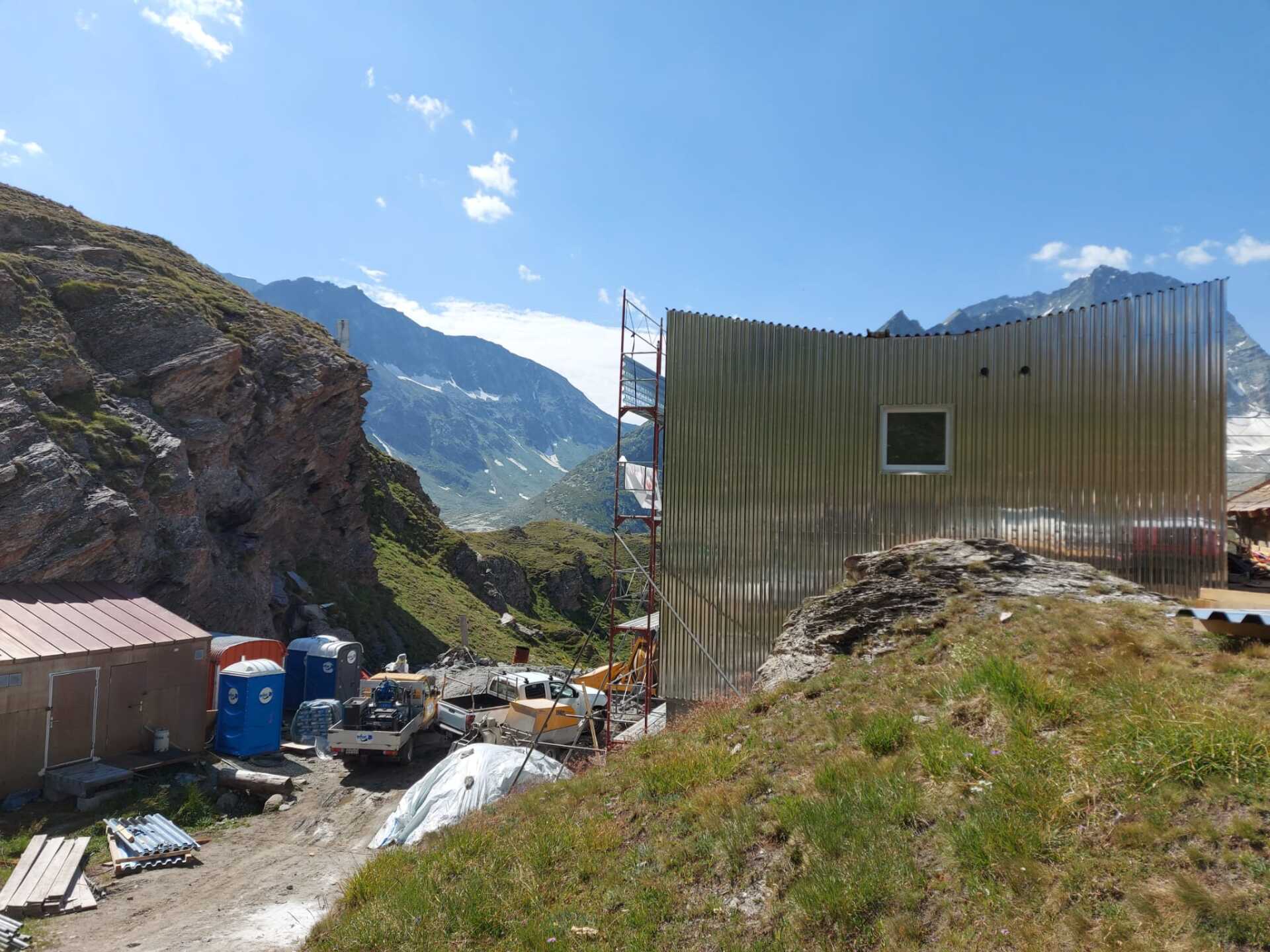 Un bâtiment est en construction au sommet d'une colline avec des montagnes en arrière-plan