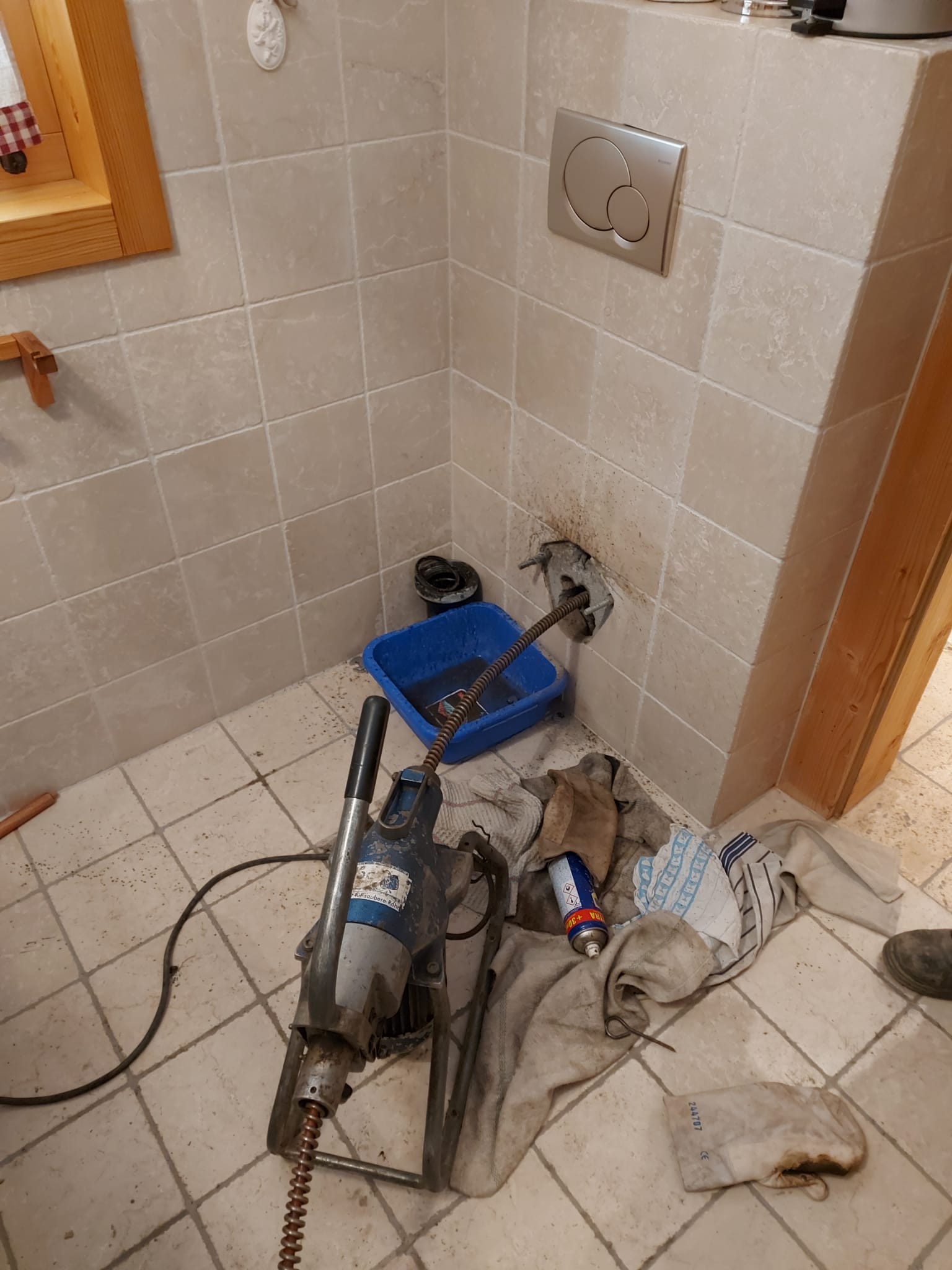 Un déboucheur de canalisations est posé sur le sol d'une salle de bain.