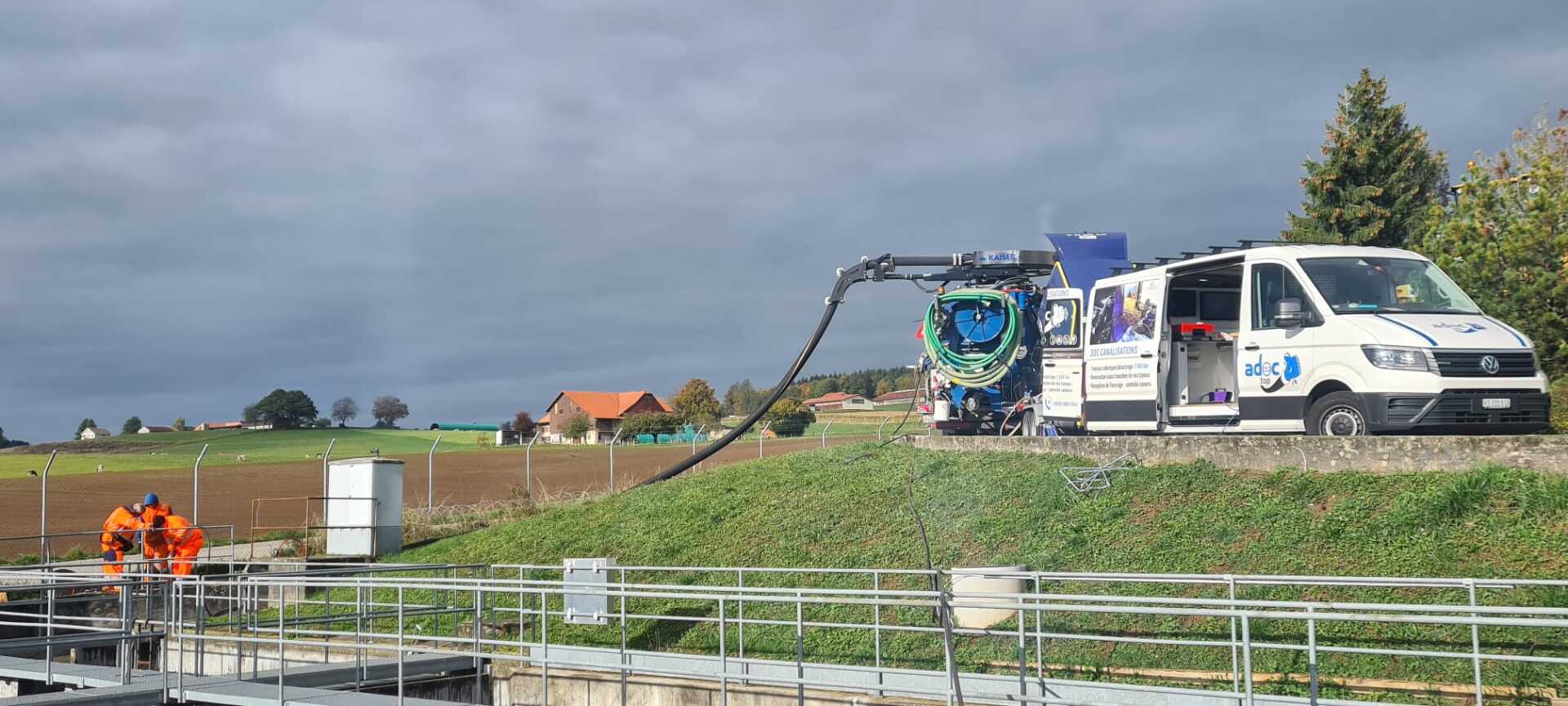 Une camionnette blanche est garée sur le bord de la route à côté d'un champ.