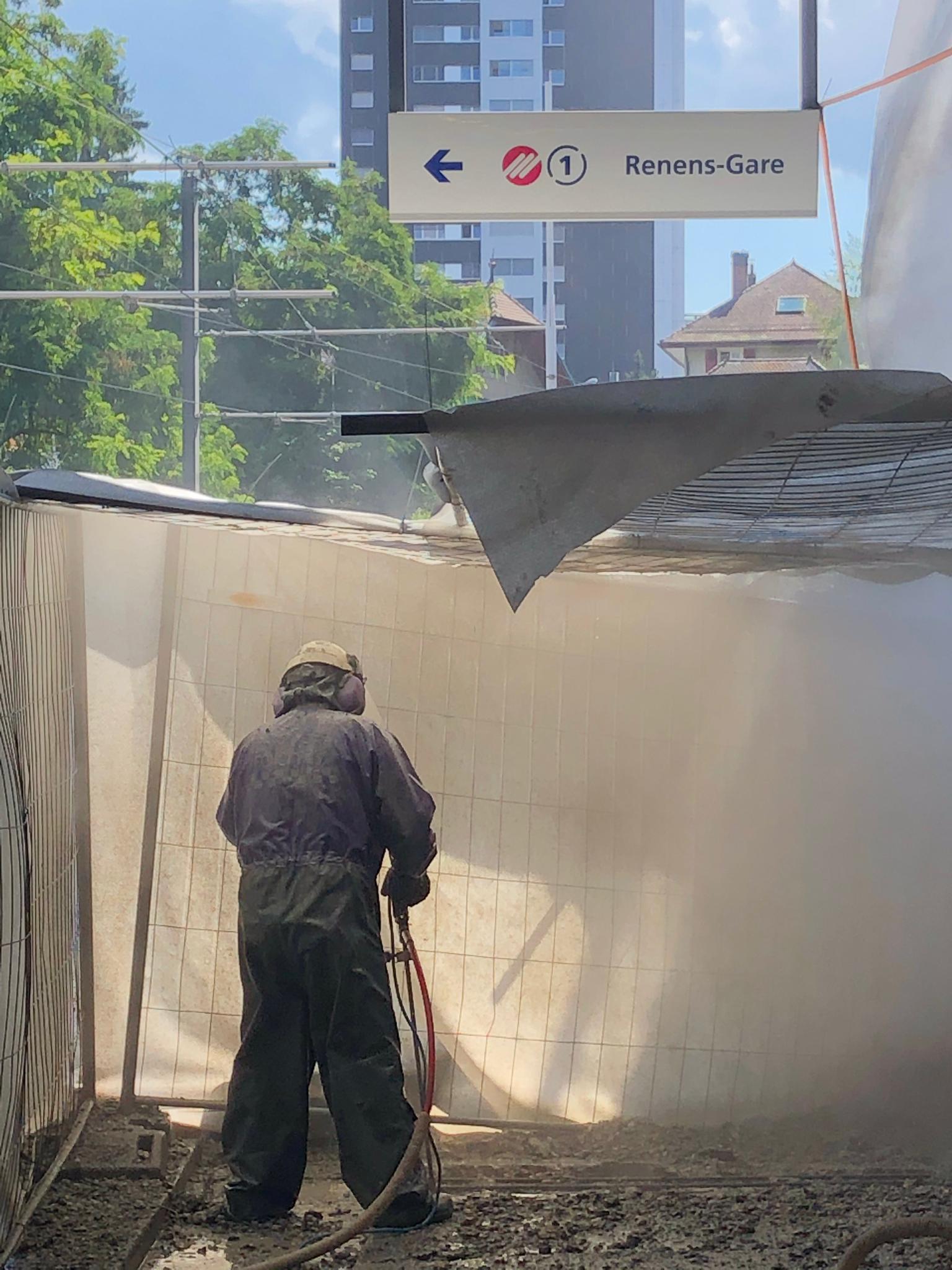 Un homme se tient devant un bâtiment et pulvérise de la peinture dessus.