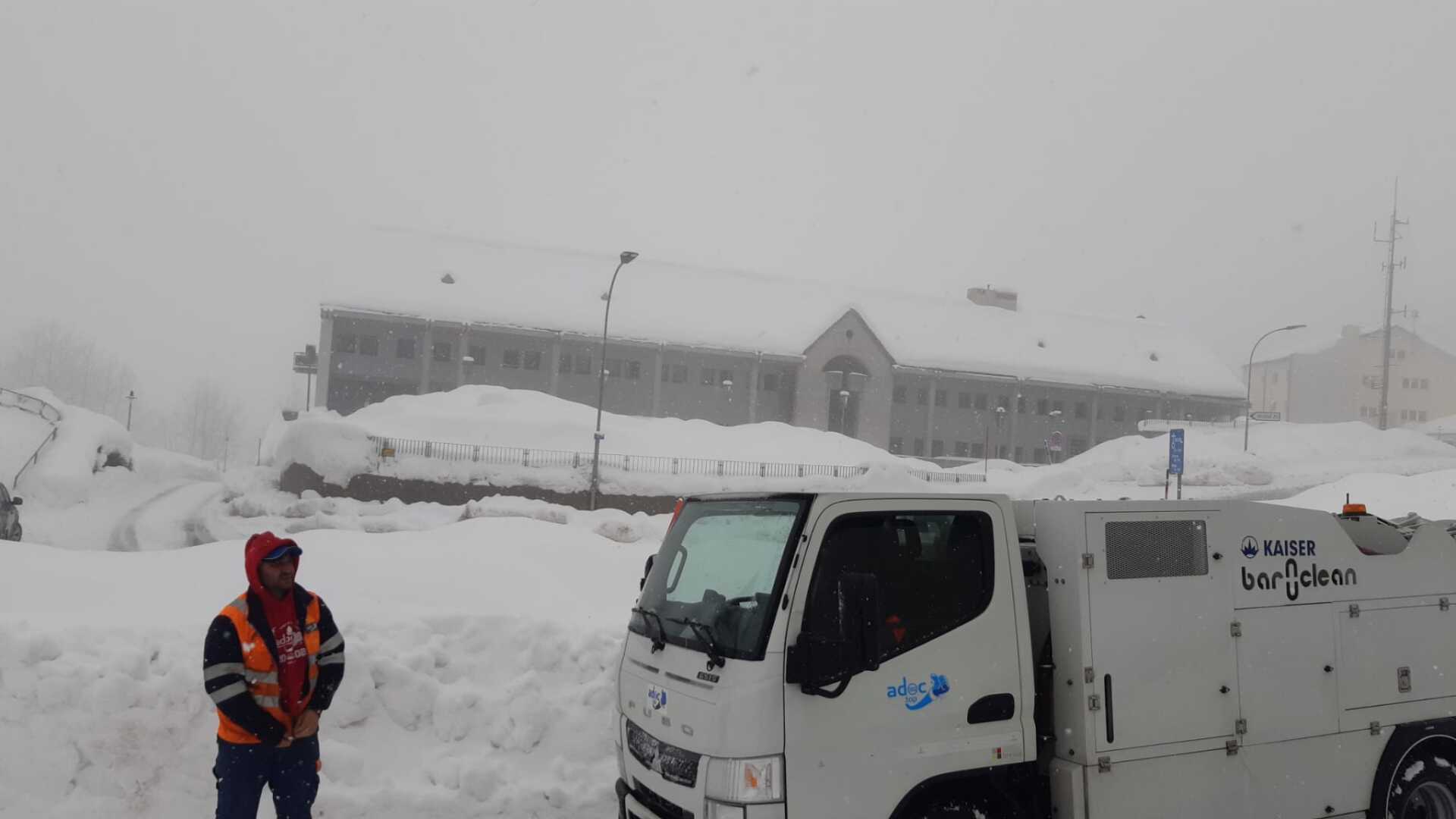 Un homme se tient à côté d'un camion blanc dans la neige.