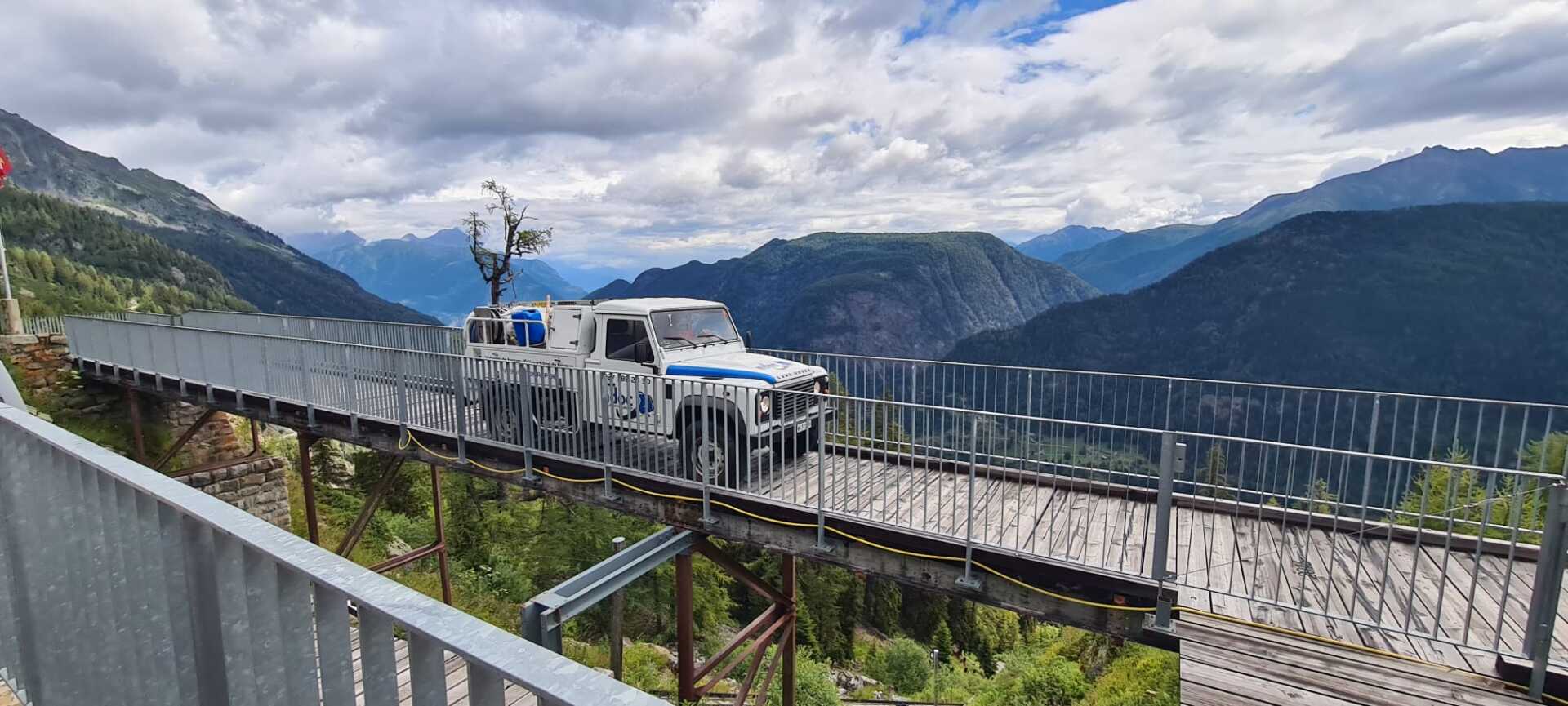 Un camion roule sur un pont avec des montagnes en arrière-plan.