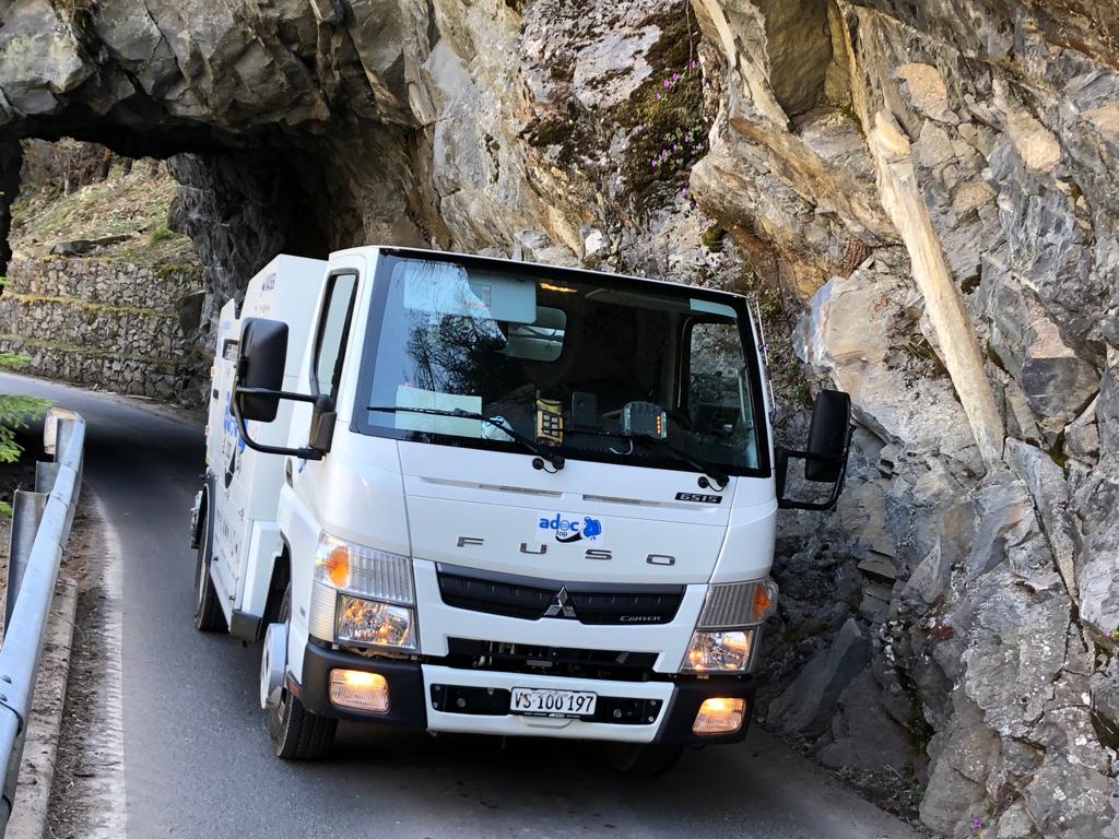 Un camion blanc roule sur une route de montagne.