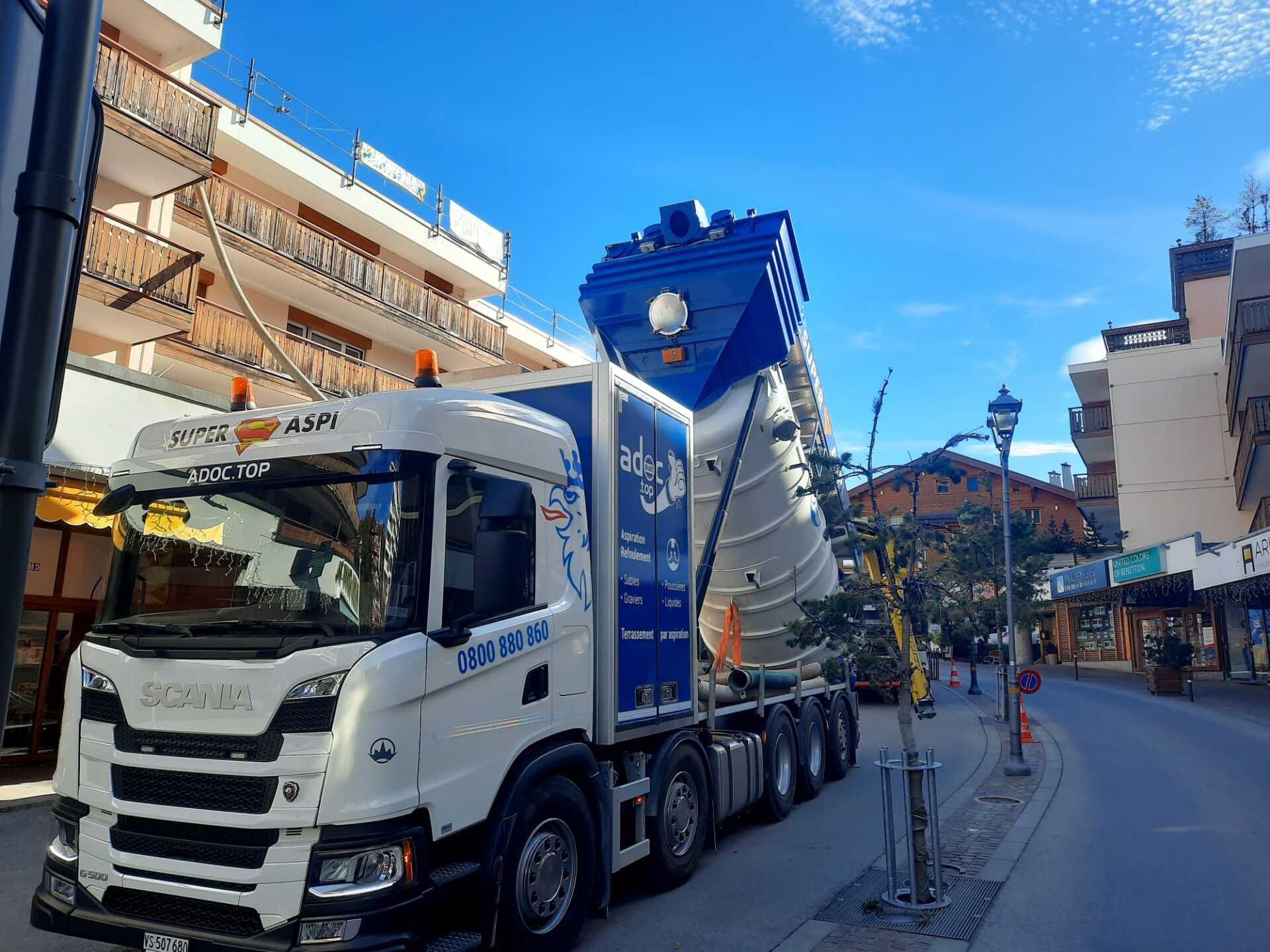 Un camion blanc et bleu est garé sur le bord de la route.