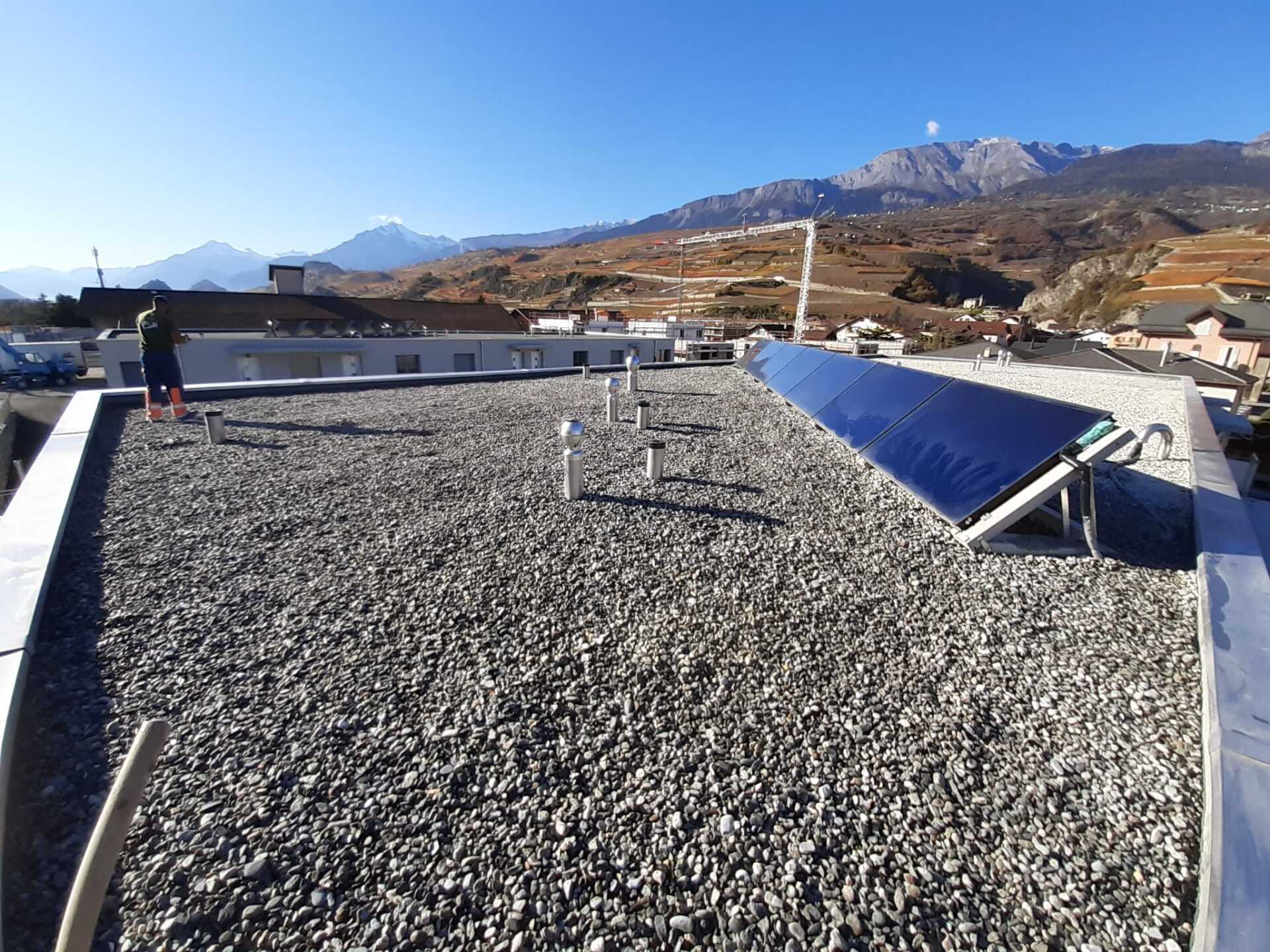 Un toit avec beaucoup de gravier et des panneaux solaires dessus