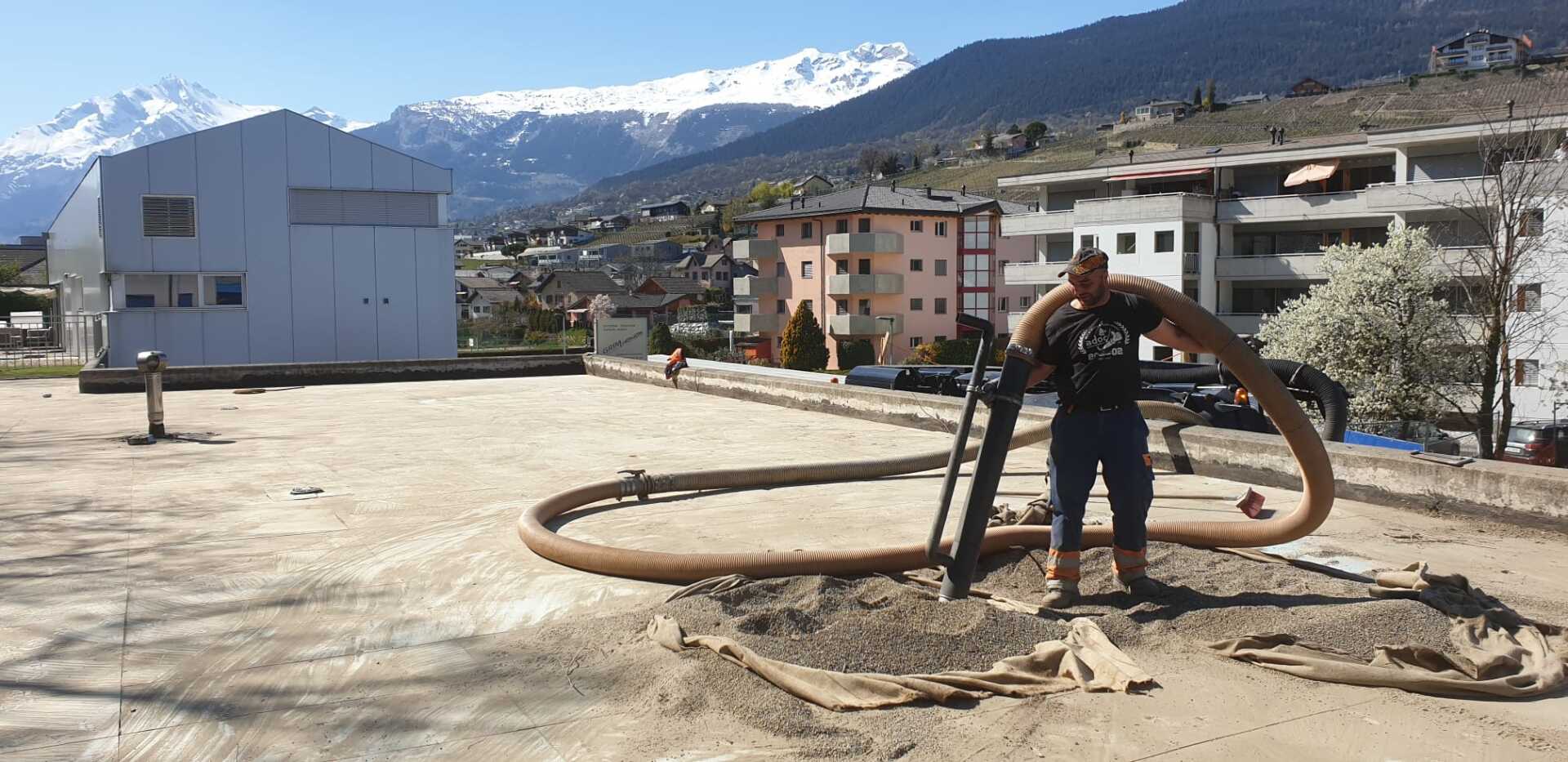 Un homme se tient debout sur un chemin de terre tenant un gros tuyau.