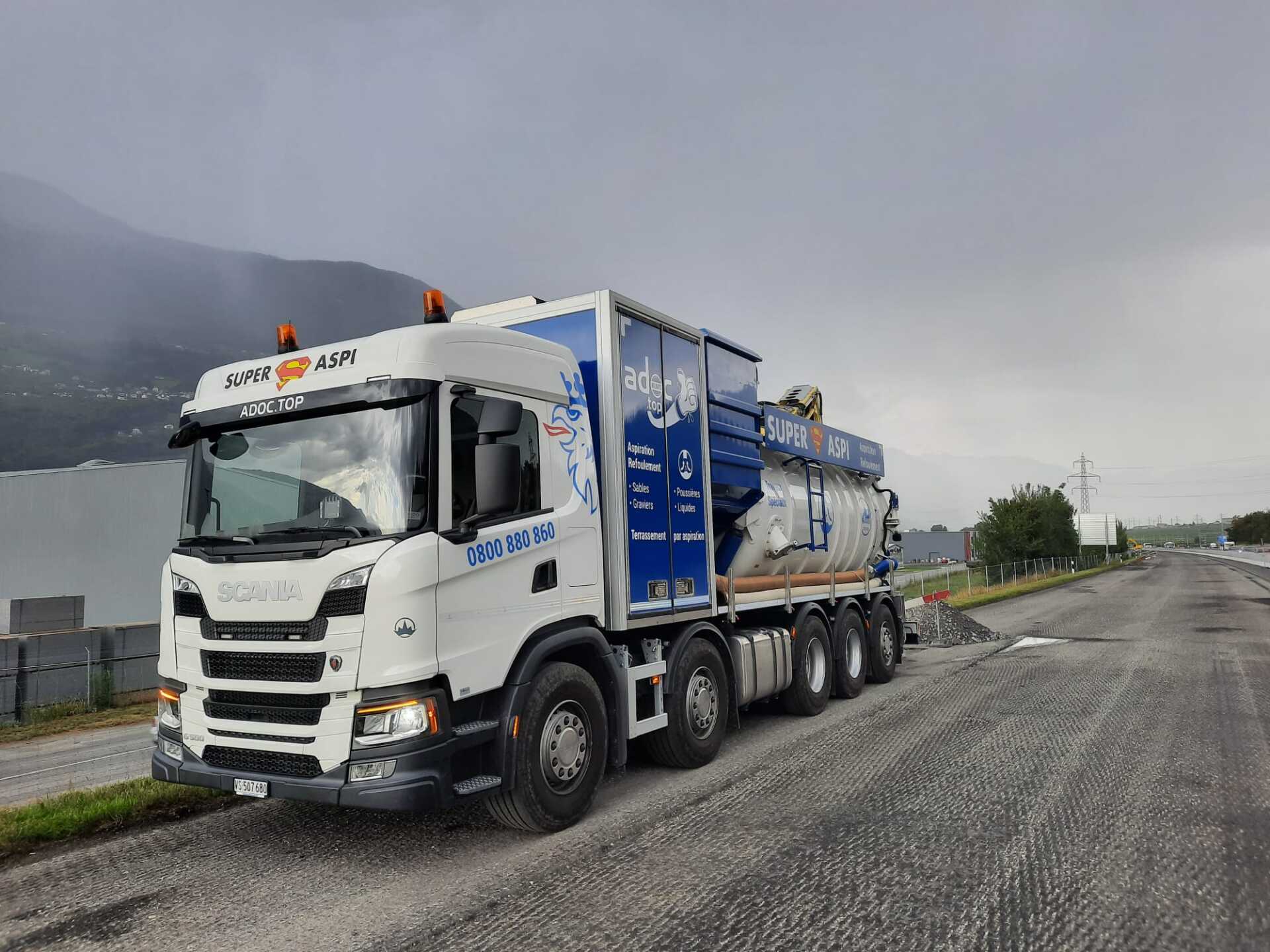 Un camion blanc et bleu est garé sur le bord de la route.