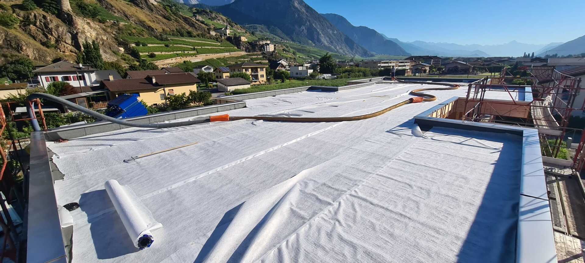 Un toit blanc est en cours d'installation sur un bâtiment avec des montagnes en arrière-plan.