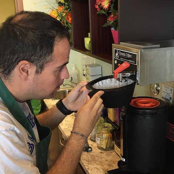 Student adding more ground coffee to coffee machine