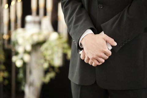 Persona a mani giunte durante una cerimonia funebre
