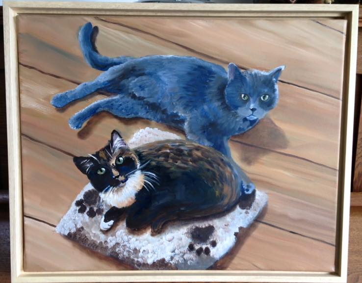 Twee geschilderde katten op hout: een blauwe kat en een driekleurige kat op een kussen.