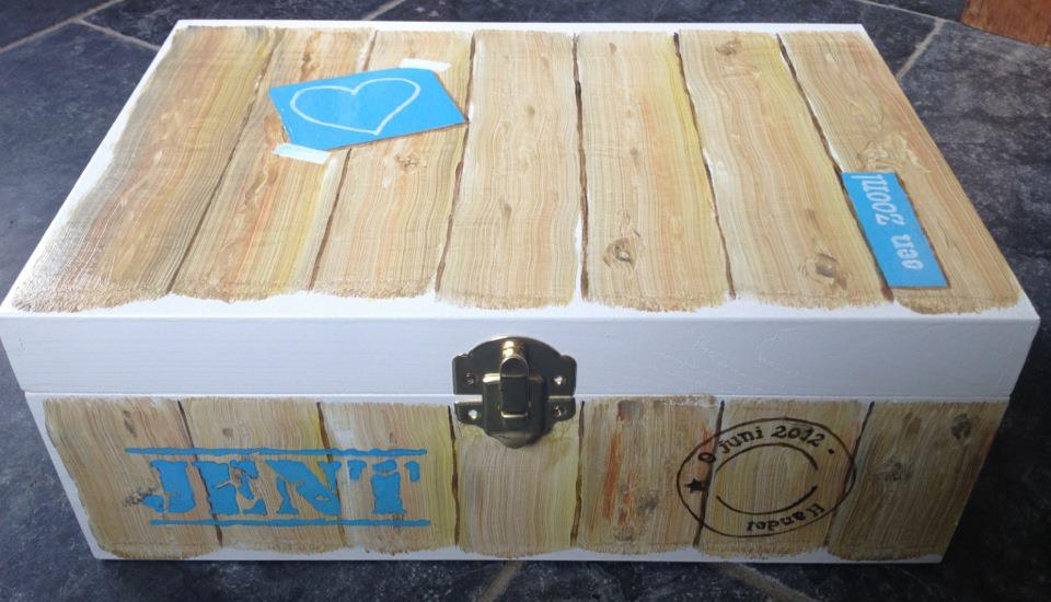 Houten krat met blauw-witte etiketten en een metalen sluiting aan de bovenkant.