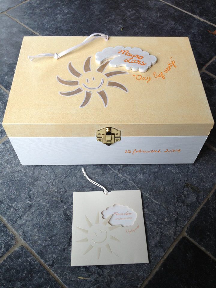 Decoratieve goud-witte geschenkdoos met bijpassend label op een donkere stenen ondergrond.