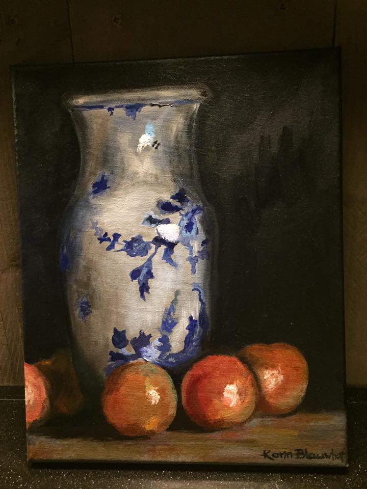 Stilleven van een blauw-witte vaas met sinaasappels op een donkere achtergrond.