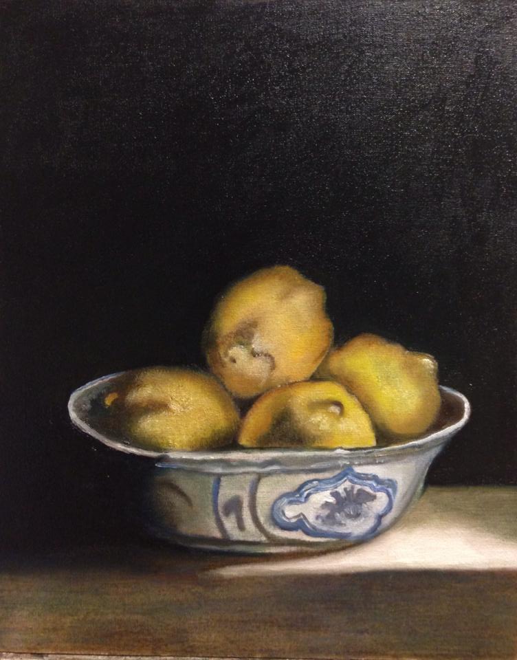 Een schaal met geel fruit op een tafel tegen een donkere achtergrond.