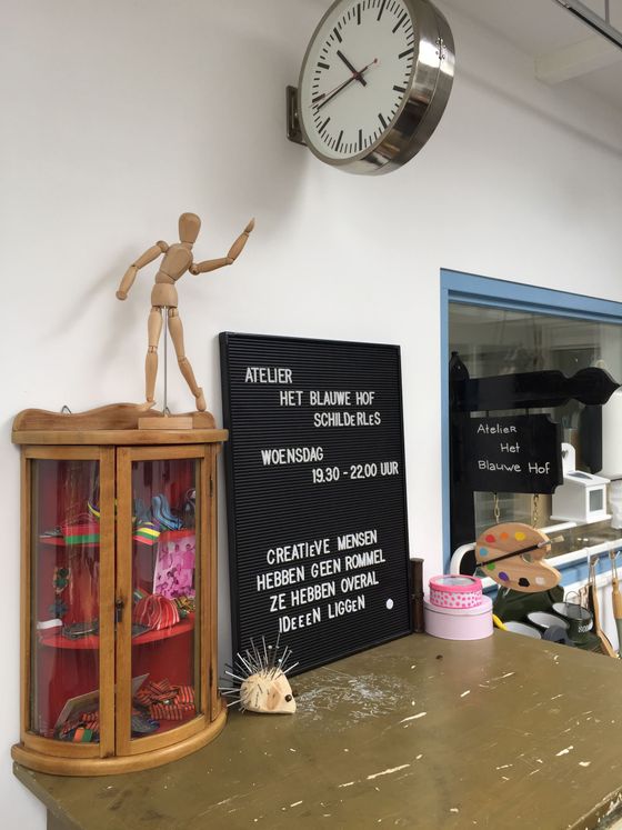 Plank in het kunstlokaal met paspop, wandklok, zwart menubord en diverse knutselspullen.