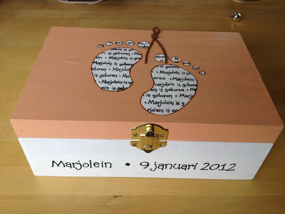 Decoratieve houten doos met deksel in de vorm van een paardenbloem en handgeschreven datum, op een lichte achtergrond.