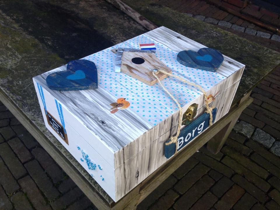Een kartonnen doos met een Nederlandse vlag en blauwe hartjes, met het opschrift 