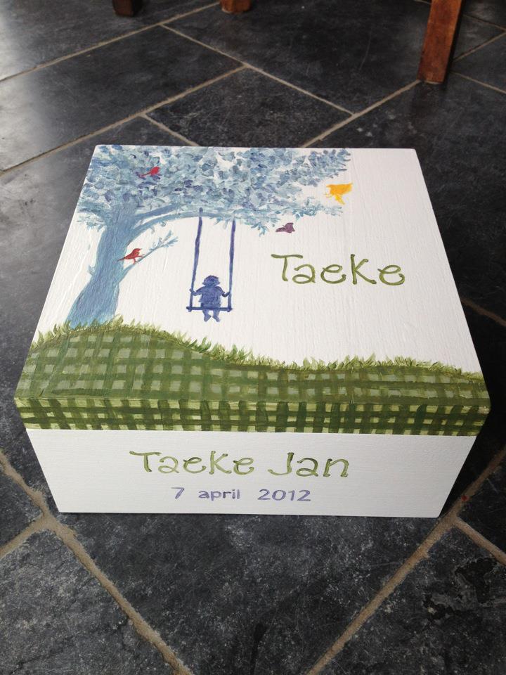 Witte geschenkdoos met een afbeelding van een boom en een schommel, met het opschrift 