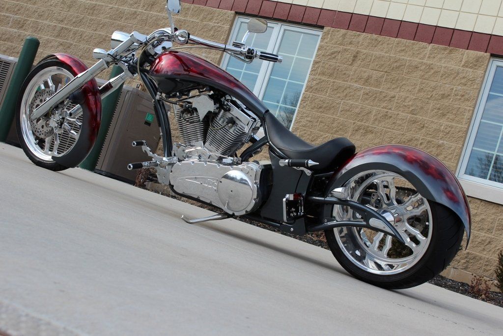Custom maroon and chrome chopper motorcycle parked outdoors by a building