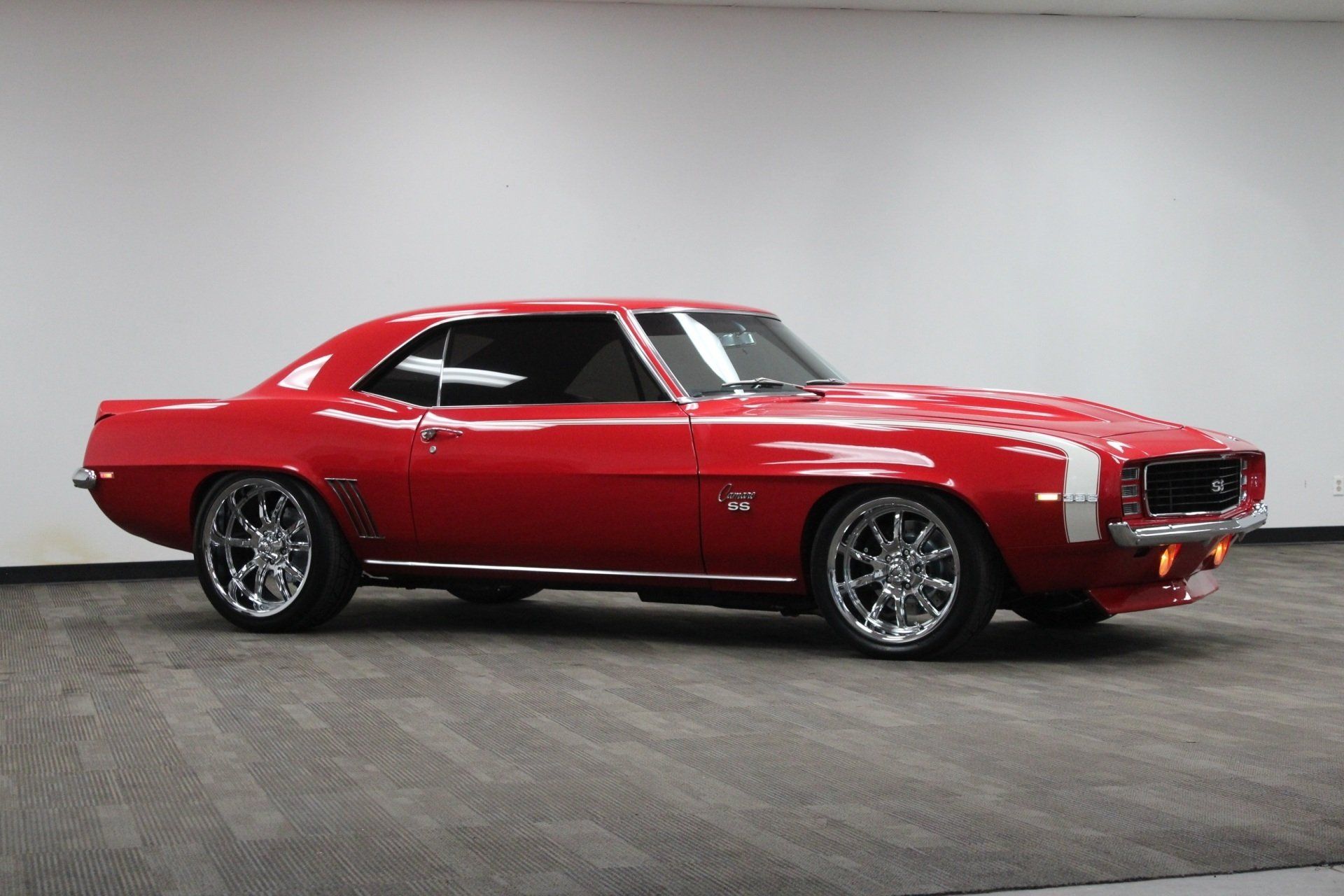 Red classic muscle car in a studio, side view on a gray floor.