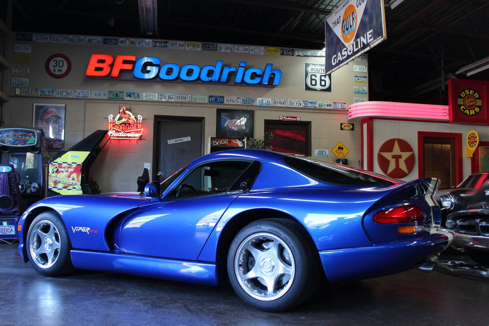 Blue sports car in an indoor showroom with BFGoodrich signage and racing-themed decor