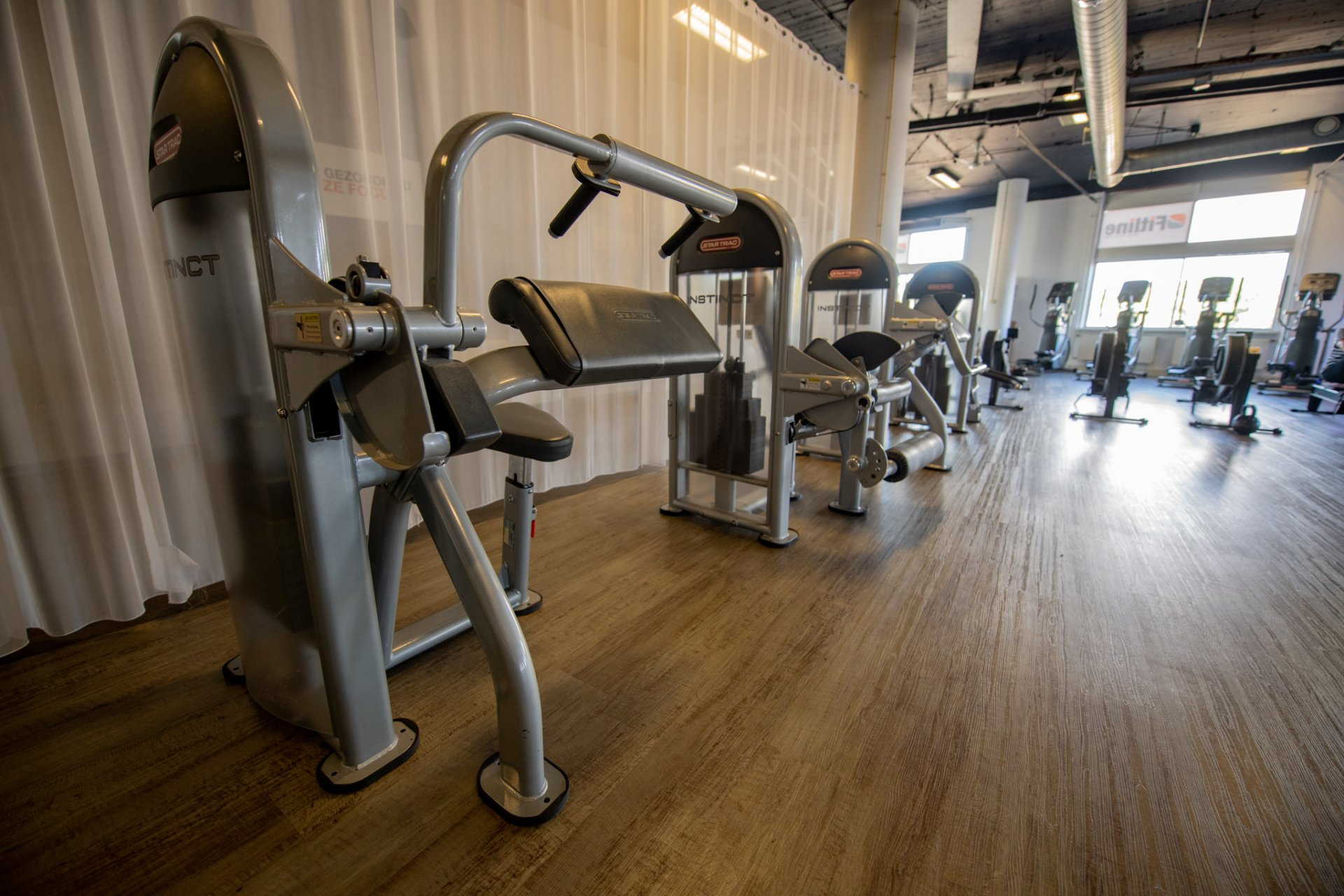 een sportschool met veel fitnessapparatuur op de vloer.