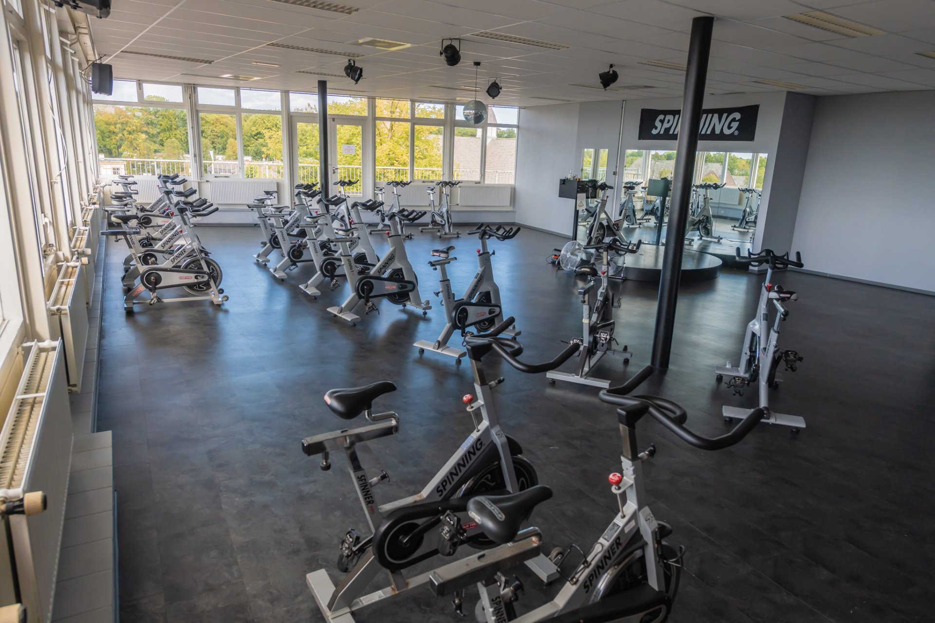 een grote kamer vol met veel hometrainers in een sportschool.