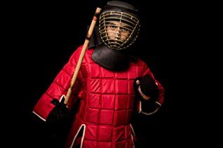 Man Wearing Red Armor And Holding Escrima Stick — Richmond, KY — Richmond School of Karate Man Wearing Red Armor And Holding Escrima Stick — Richmond, KY — Richmond School of Karate