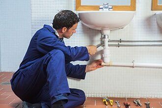 Plumber Repairing a Sink — Plumbing Contractor in Sacramento, CA Plumber Repairing a Sink — Plumbing Contractor in Sacramento, CA