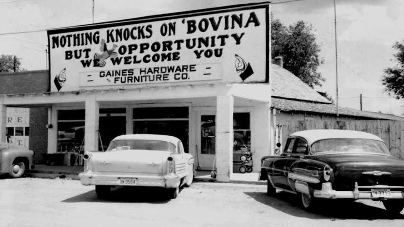 Two cars are parked in front of a building that says nothing knocks on bovina