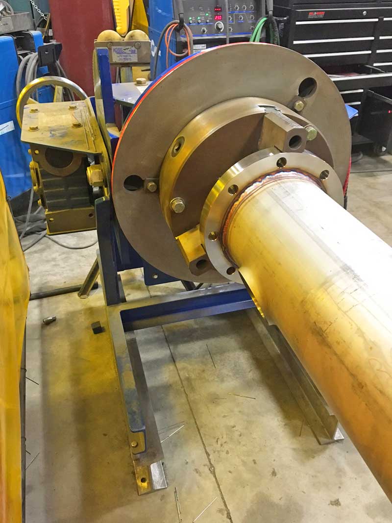A large pipe is sitting on top of a machine in a factory.
