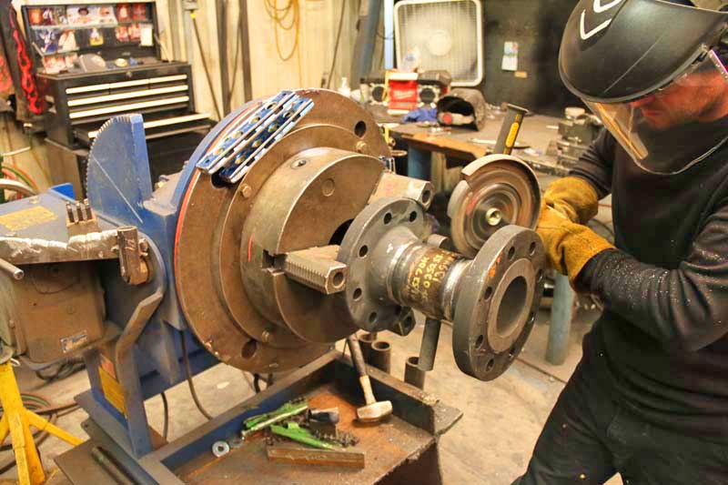 A man wearing a welding helmet is working on a piece of metal.