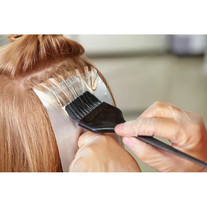 A woman is getting her hair dyed by a hairdresser.