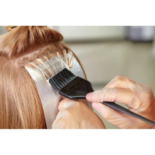 A woman is getting her hair dyed by a hairdresser.