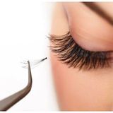 A close up of a woman 's eye with long eyelashes and a pair of tweezers.