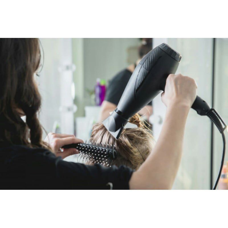 A woman is getting her hair blow dried by a hairdresser.