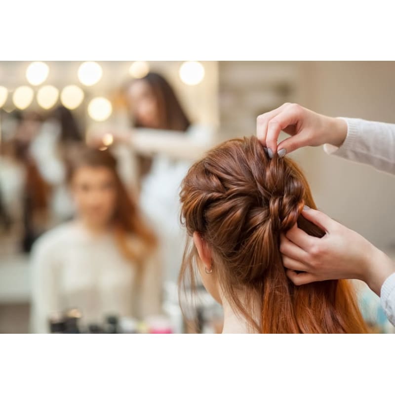 A woman is getting her hair done by a hairdresser in a salon.
