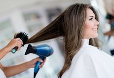 A woman is getting her hair blow dried in a salon.