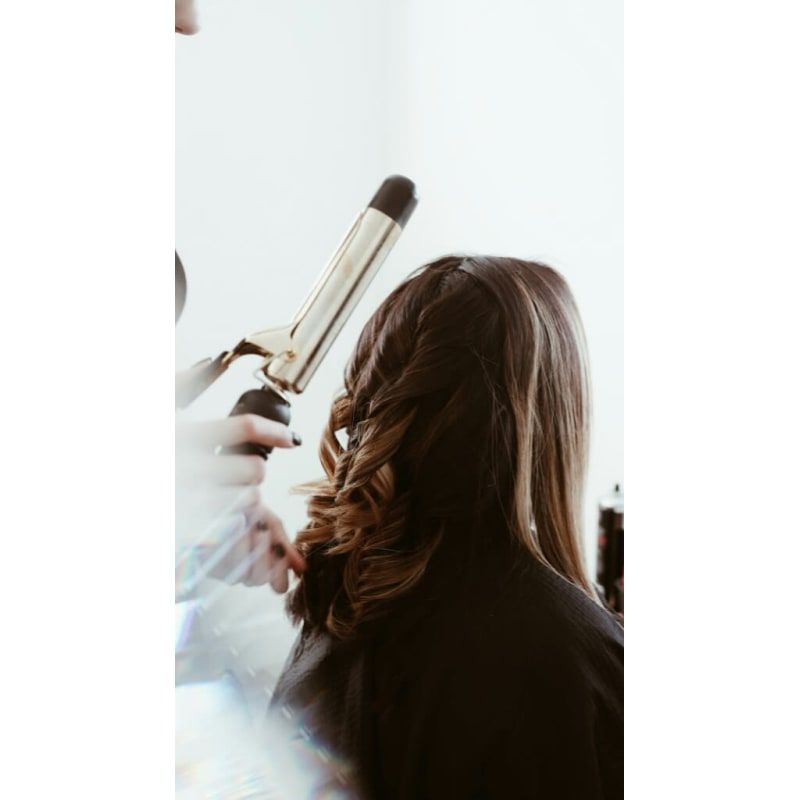 A woman is getting her hair curled by a hairdresser.