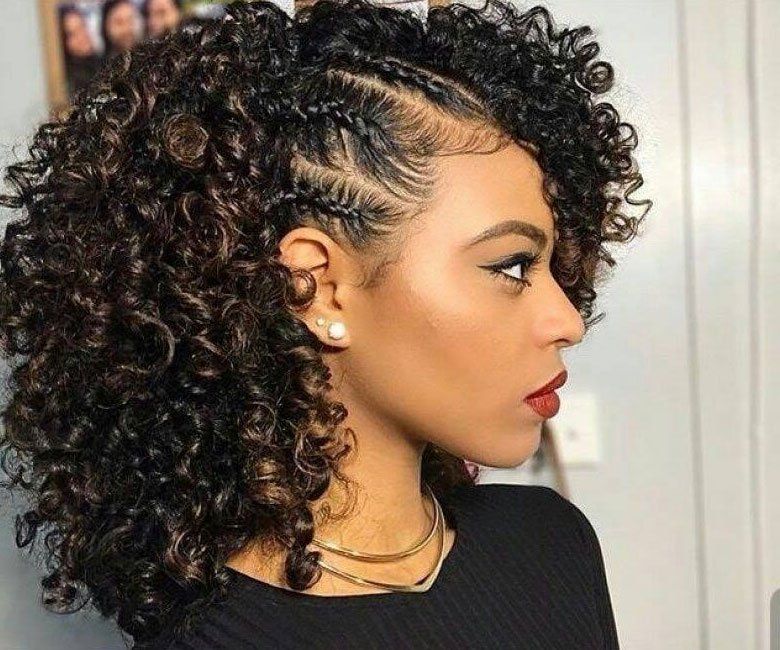 A woman with curly hair is wearing a black shirt and earrings.