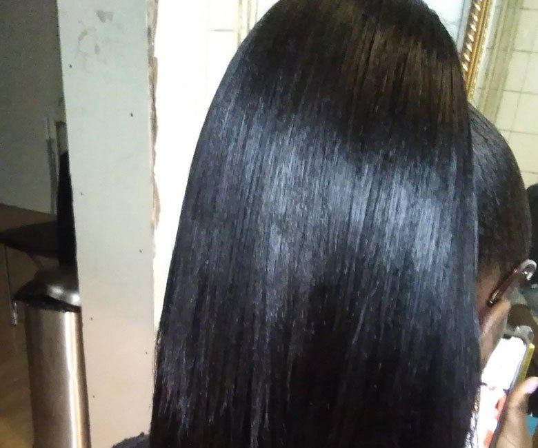 A woman with long black hair is standing in front of a mirror