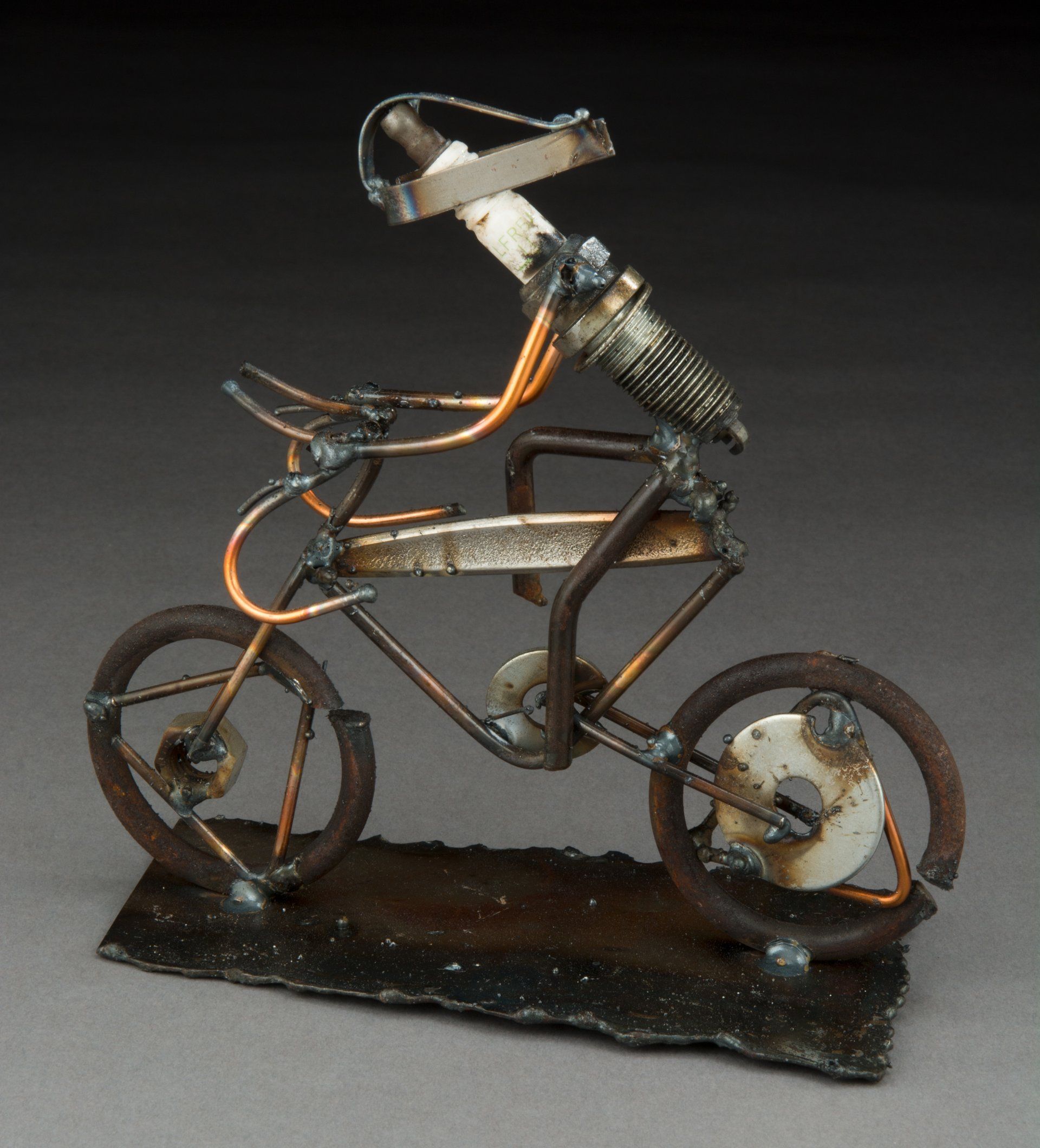 Sparkplug Sculpture of Figurine Racing a Bike