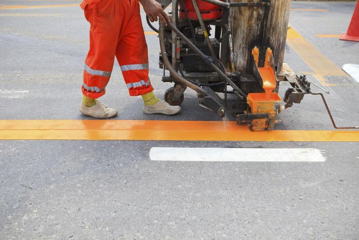 someone drawing a orange pavement markings